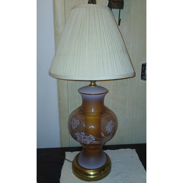 Transparent pink glass ginger jar lamp with handpainted white and gold lilies. Interior orange-y column, with tarnished...