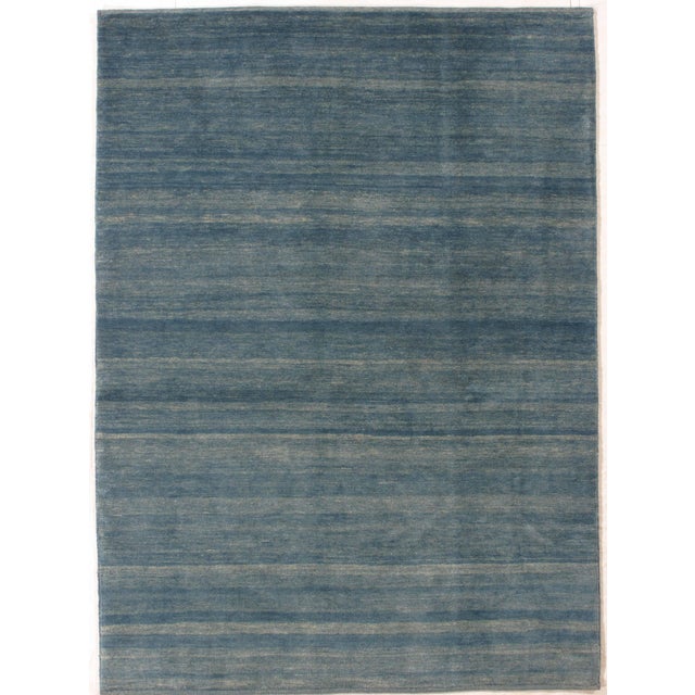 Vintage Hand-knotted Persian Lori Gabbeh rug featuring a soft blue field with subtle horizontal striations and natural...