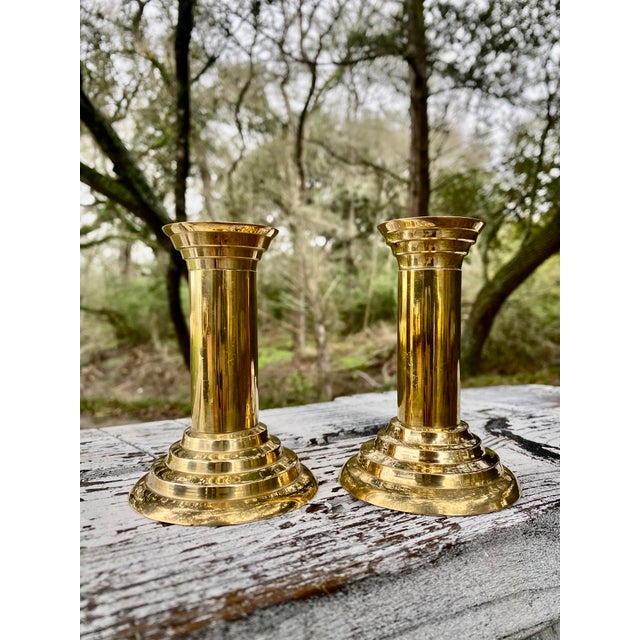 This exceptional duo of brass candle holders exemplifies a refined fusion of neoclassical elegance and minimalist form....