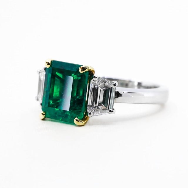 Platinum and 18k ring with top gem 3.88 carat Colombian Muzo emerald and two cloroless sheild cut diamonds weighing 1.02...