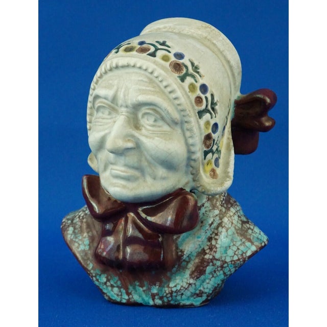 Item description: a stunning sculpture depicting the bust of an elderly woman wearing a bonnet decorated with incised...