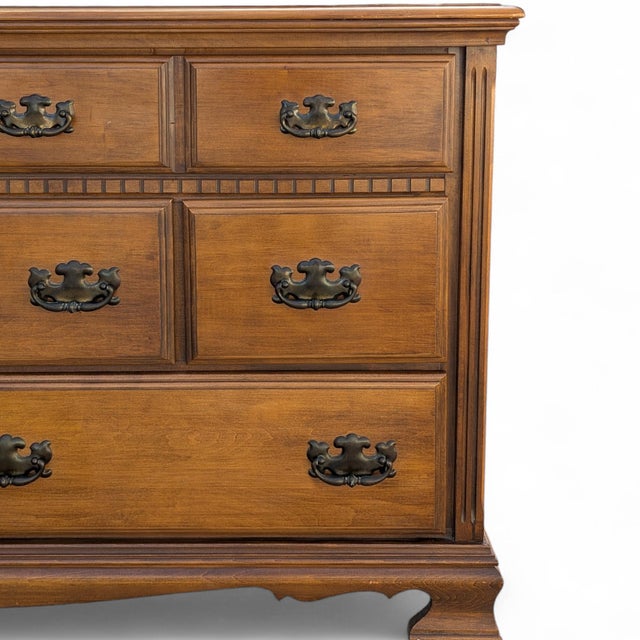 A generously scaled traditional wood dresser with nine drawers, bracket feet, framed drawer fronts, fluted corner details,...