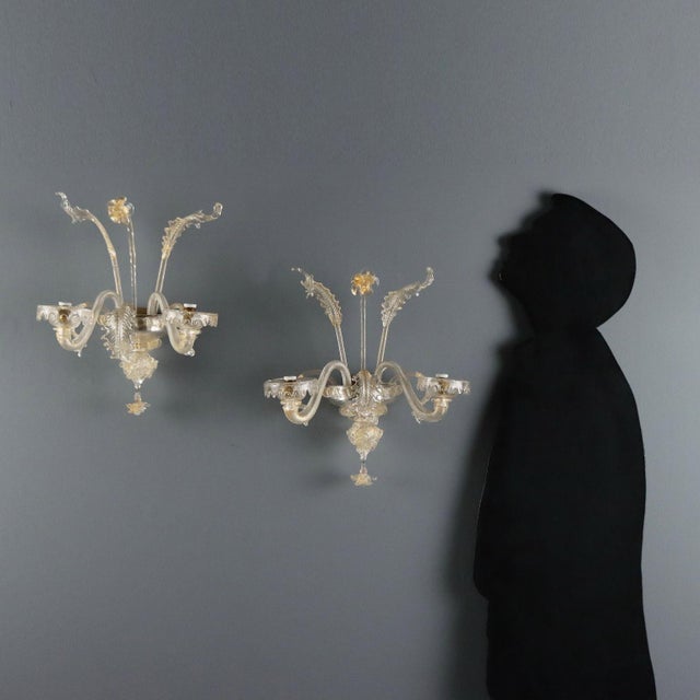 A pair of Venetian blown glass wall sconces, characterized by a transparency enhanced by delicate golden hues. The two...