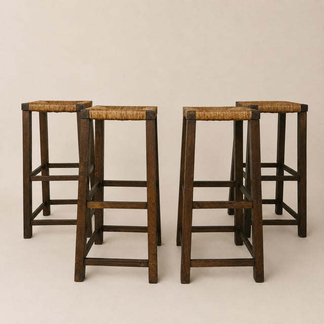 A matched set of four unmarked Dutch bar stools dating to the 1960s, constructed in dark-stained oak with tightly woven...