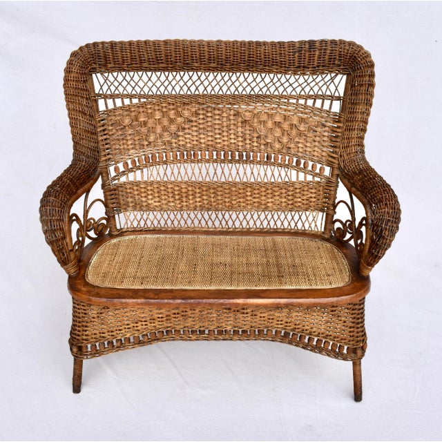 American Victorian wicker roll design high back loveseat with spindles and bobbins on the back and apron and cane seat....