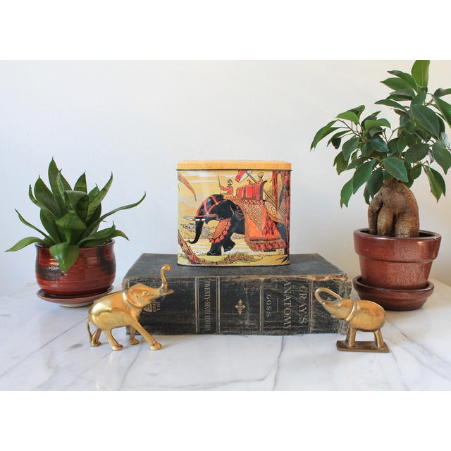 Vintage tin with elephant and royalty. Made in England. Makers mark on the side. Some fading.