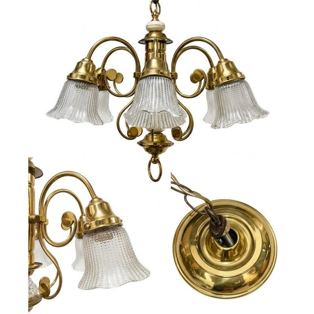 An elegant vintage chandelier featuring a polished brass frame with graceful curved arms and decorative white porcelain...