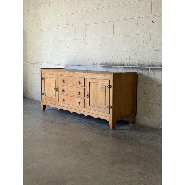 This low sideboard features a central stack of three drawers flanked by two side doors opening to interior shelving. A...