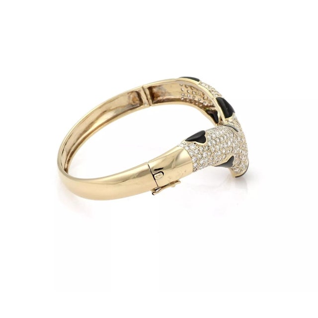 This beautiful bangle bracelet is crafted from 18k yellow gold with a polished finish. The front of the band has a wide...
