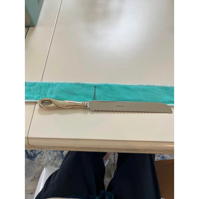 This authentic Tiffany & Co. bread knife features an elegantly sculpted loop-style sterling silver handle paired with a...