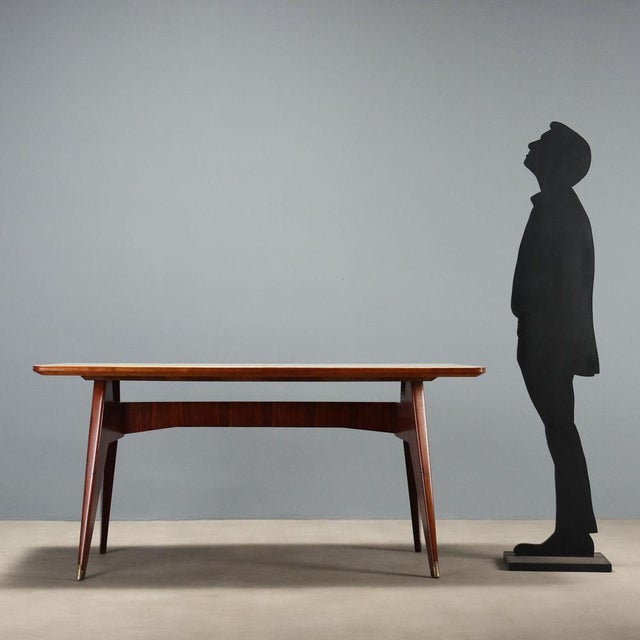 Italian-made dining table from the 1950s-1960s, featuring an exotic wood frame and a back-treated glass top, adding a...