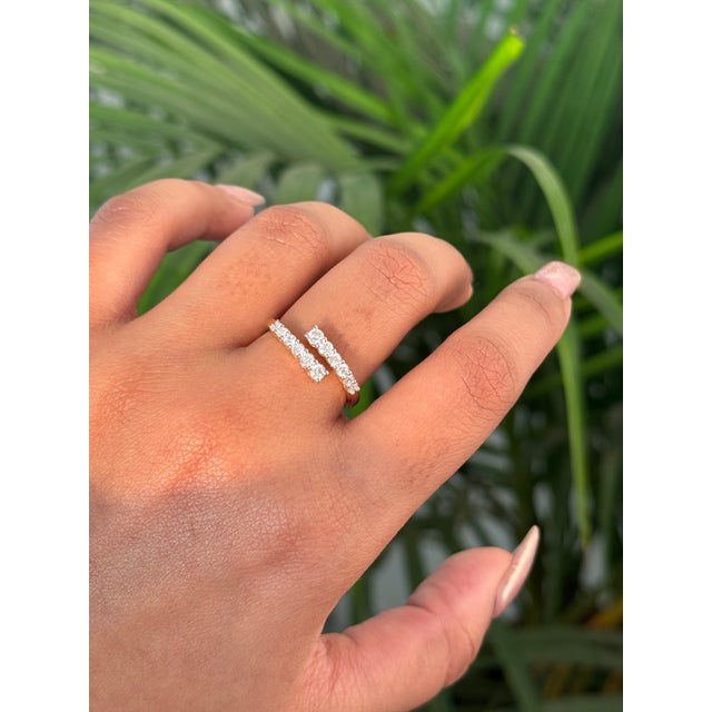 This modern diamond open-bypass ring is crafted in 14K yellow gold and features a sleek, minimalist silhouette accented...