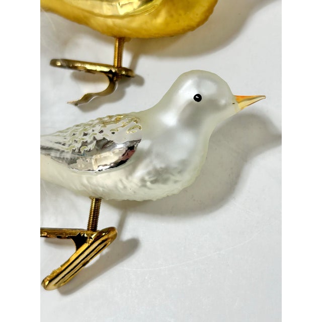Set of three vintage glass bird Christmas ornaments featuring two golden birds and one pearly white bird. Each has...