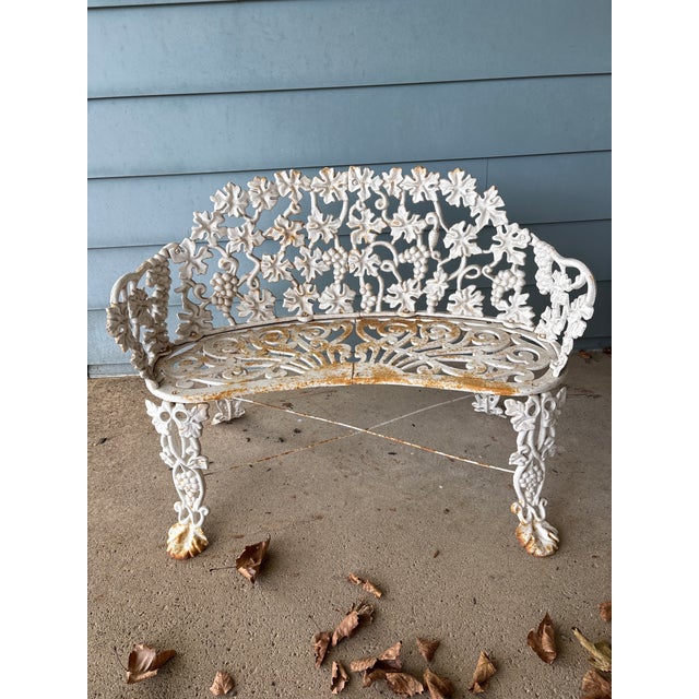 White cast iron grapevine garden table, chairs (2), and bench set. Splayed leaf leg profile. Possibly late Victorian to...