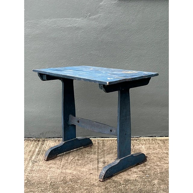 This vintage side table showcases a classic trestle-style construction, its rectangular wooden top resting atop two...