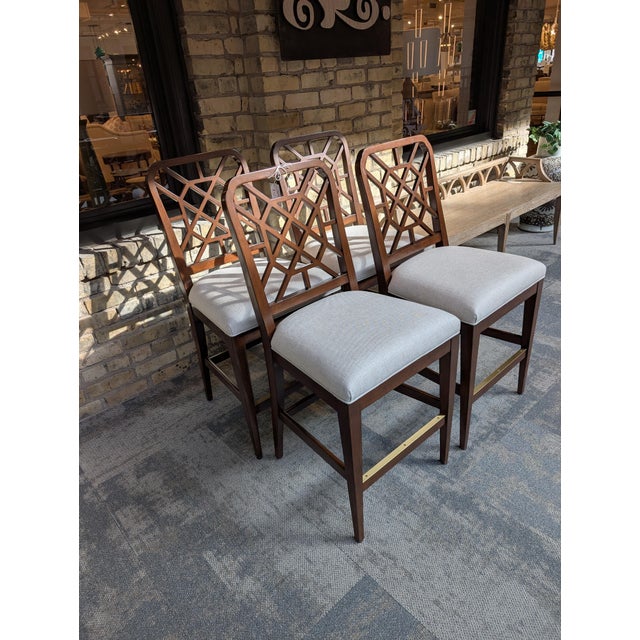 Four brand new, never used Woodbridge Merrion Counter Stools that features a pierced geometric fretwork back, an...