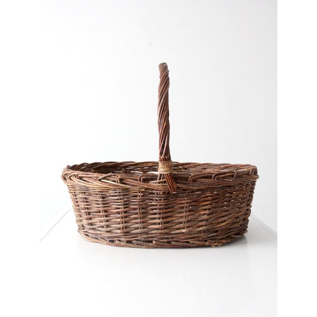 Vintage wicker gathering basket with a generous oval form and beautifully arched handle. The warm woven texture and rich...
