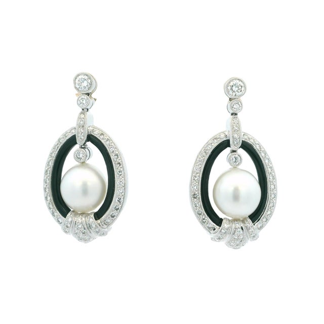Elegant 1990s earrings crafted in 18K white gold, featuring luminous 14mm South Sea pearls framed by polished black onyx...