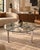Sleek 1970s Mid-Century Modern round coffee table featuring a clear glass top supported by a sculptural chrome X-form...