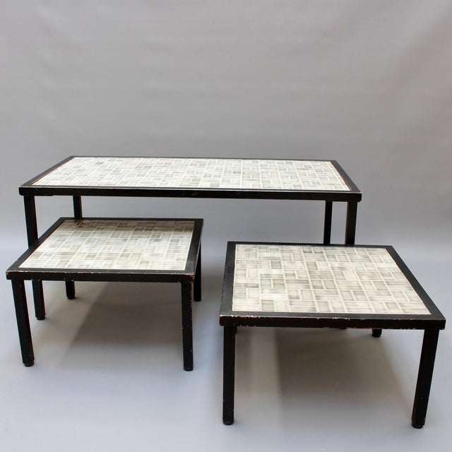 Set of three vintage french tiled coffee and end tables (circa 1960s). Subdued hues shade the ceramic tiles which sit upon...