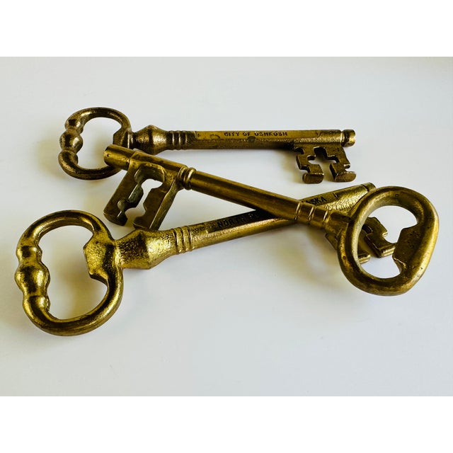 Set of 3 oversized brass key bottle openers. Two are possibly commemorative keys to the cities of Oshkosh, Wisconsin and...