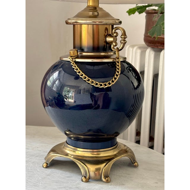 Stunning mid-century indigo blue table lamp with pleated shade and ornate brass details, including scroll feet and chain....