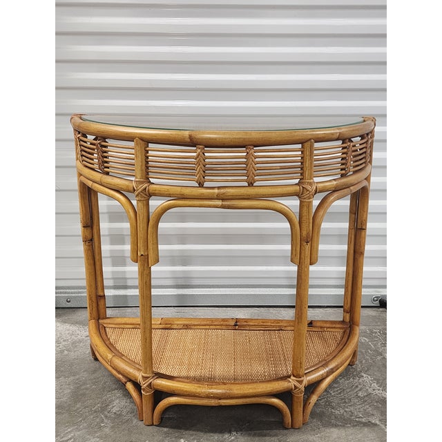 Mid-Century boho chic bamboo and rattan demi-lune console table with custom glass top in the style of Franco Albini. The...