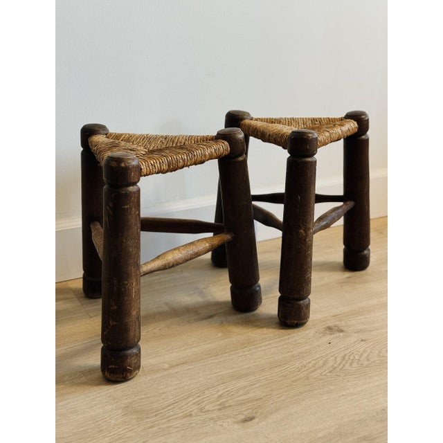 A charming pair of French rush seat stools in the style of Charles Dudouyt, featuring thick, turned legs with softly worn...