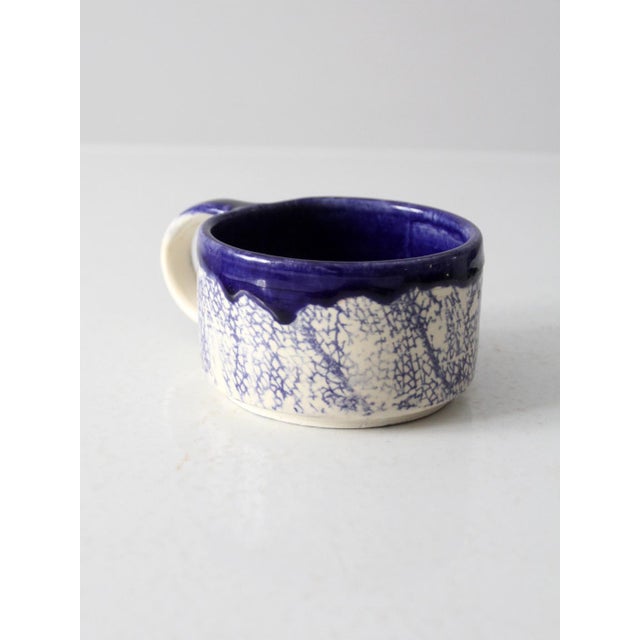 This vintage studio pottery mug stands out with its distinctive glaze and form. Signed by the artist, it features a...