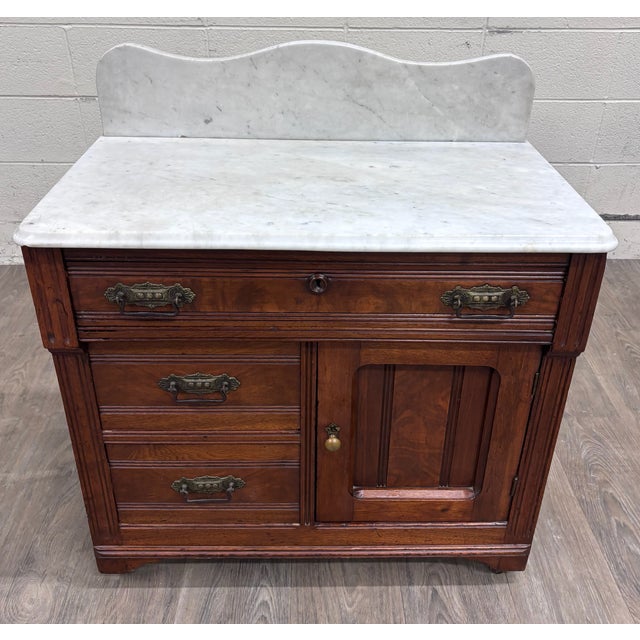 This is a stunning antique Victorian Eastlake walnut washstand, circa 1880–1900, featuring a white marble top and shaped...
