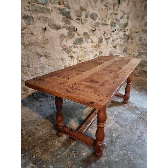 This vintage French dining table dates from 1950–1970 and is crafted entirely from solid oak. The table features a...