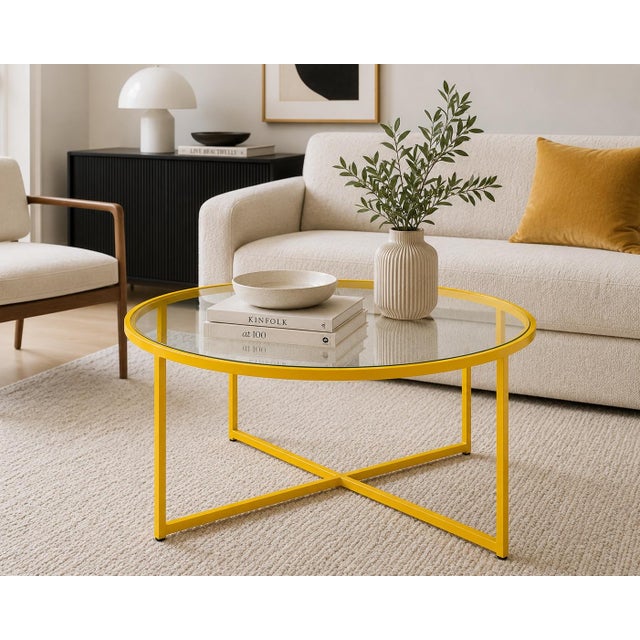 A bold minimalist round coffee table featuring a vibrant canary yellow geometric metal frame and clear glass top. Airy,...