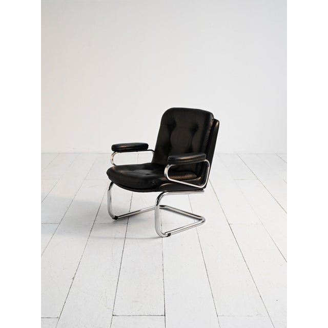 Scandinavian armchair from the 1970s with a chromed metal frame and a black leather seat with buttoned upholstery. Vintage...