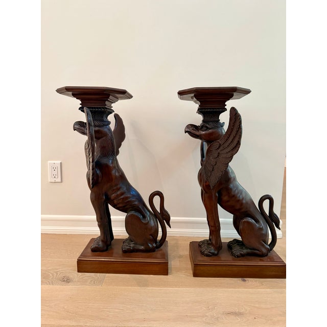 A dramatic pair of hand-carved pedestal tables, each fashioned as a mythological winged griffin — part eagle, part lion —...