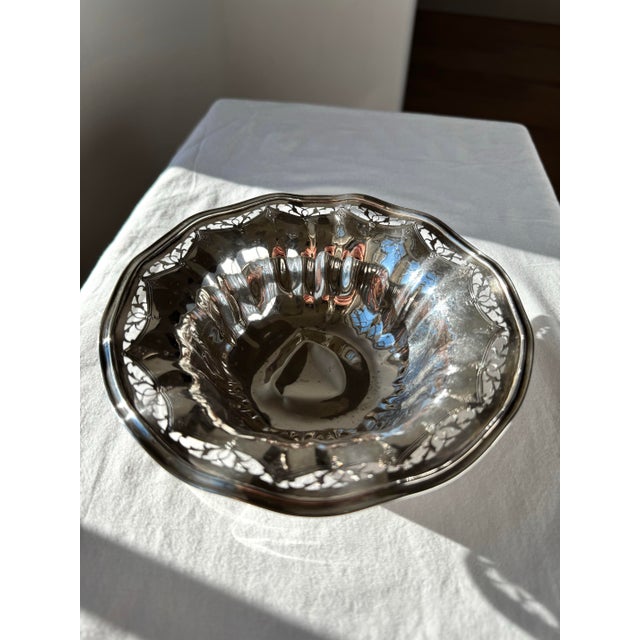 Antique sterling-style silver bowl featuring an intricately pierced rim adorned with detailed floral and scrolling motifs....