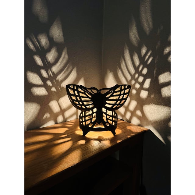 A vintage cast iron butterfly table lamp featuring an openwork design that transforms light into part of the piece itself....