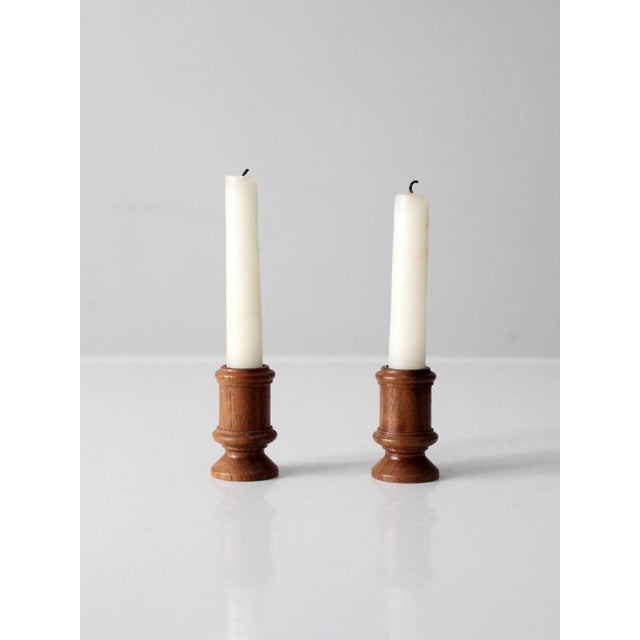 A pair of vintage turned wood candlestick holders dating to the early 20th century, exemplifying classic American Colonial...