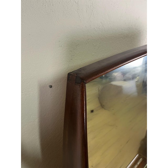 Mirror with a finely curved wooden frame and thick glass shelf, Italian-made in the 1950s. The mirror has been carefully...