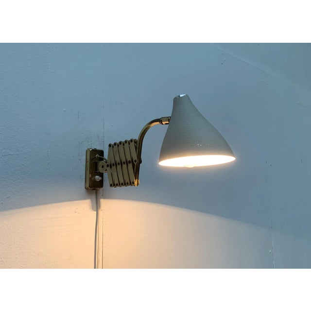 Mid Century wall sconce with flexible scissor arm. Striking is the finely executed scissor arm, which can expand and...
