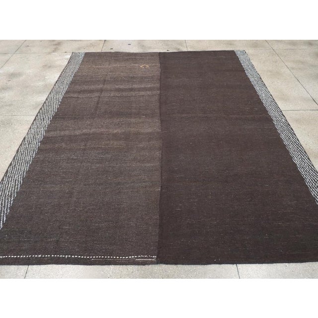 This mid-20th century Turkish flatweave Kilim rug, embodies a minimalist and rustic aesthetic with its understated design...