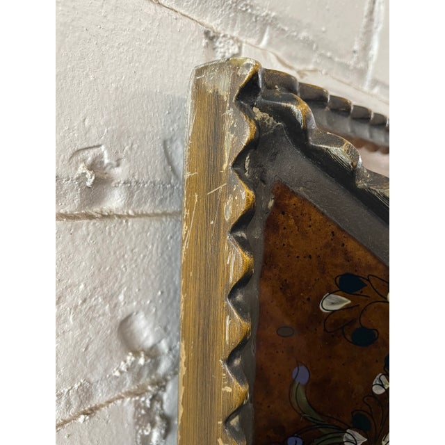 A large mirror in a frame of reverse-painted glass panels and gilt molding. Deep gold painted with floral sprays in blue...