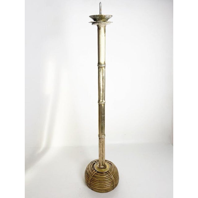 Large French floor candle holder dating from the 1970s, combining brass with a woven rattan base. Its tall, slender brass...