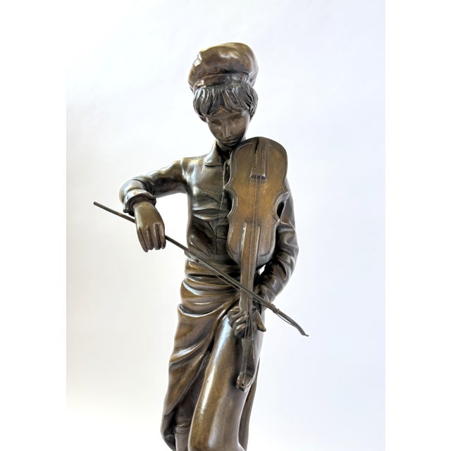 This bronze statue depicts a man gracefully playing the violin, captured in a lifelike and elegant pose. Standing 21...