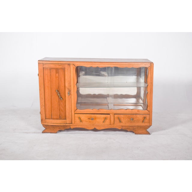 Sideboard with display case with one door and two drawers. with an asymmetrical body, it has a wooden door on the left and...