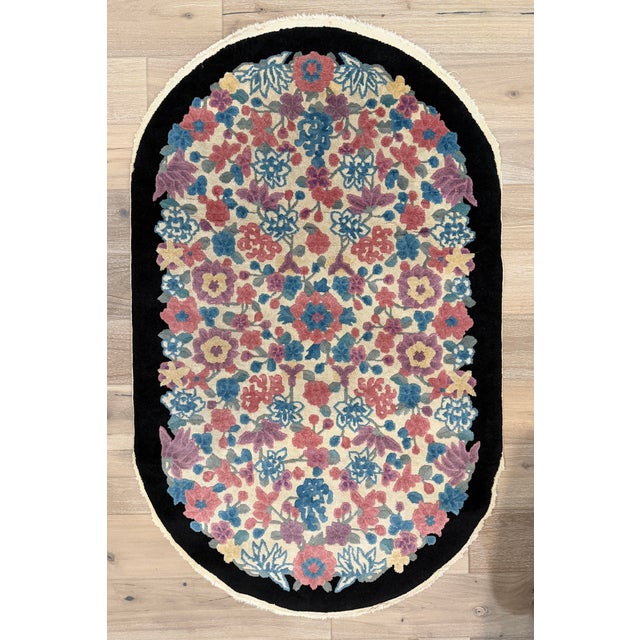 Hand-knotted wool rug measuring 3'1" x 4'11", featuring an oval format with an allover floral pattern on an ivory field...