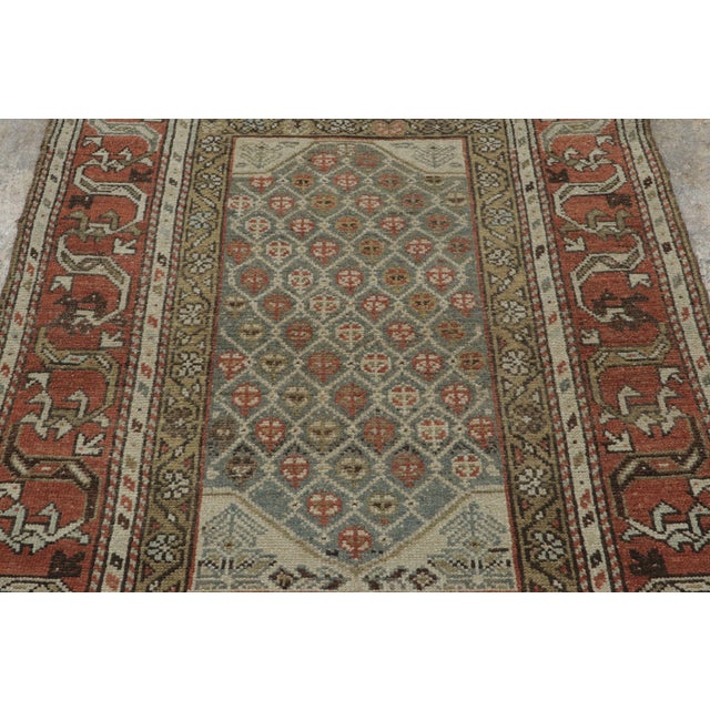 Hand-knotted in wool, this antique Persian Kurdish rug is a compelling example of tribal craftsmanship, celebrated for its...
