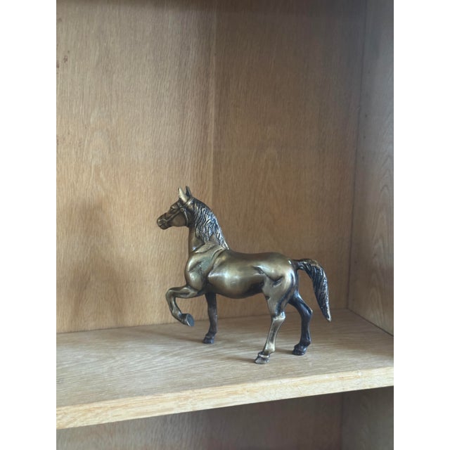 Vintage cast brass horse figurine in a prancing pose with detailed mane, bridle, and musculature. Warm aged brass finish...