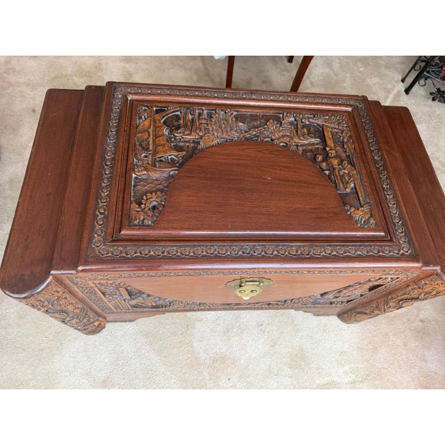 This is a heavily carved Chinese camphor wood chest made for the export market featuring intricate high relief scenes of...