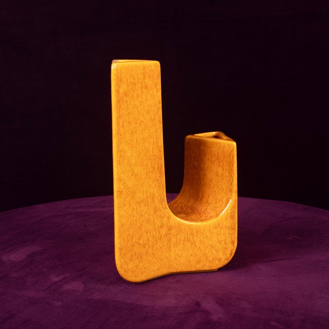 Overview a sculptural ceramic vase from the 1970s in a warm amber glaze, formed as an abstract wishbone of two upright,...