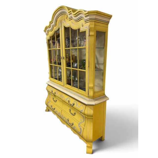 Charming vintage French Provincial style two-piece breakfront cabinet by Drexel Heritage. This statement piece features a...